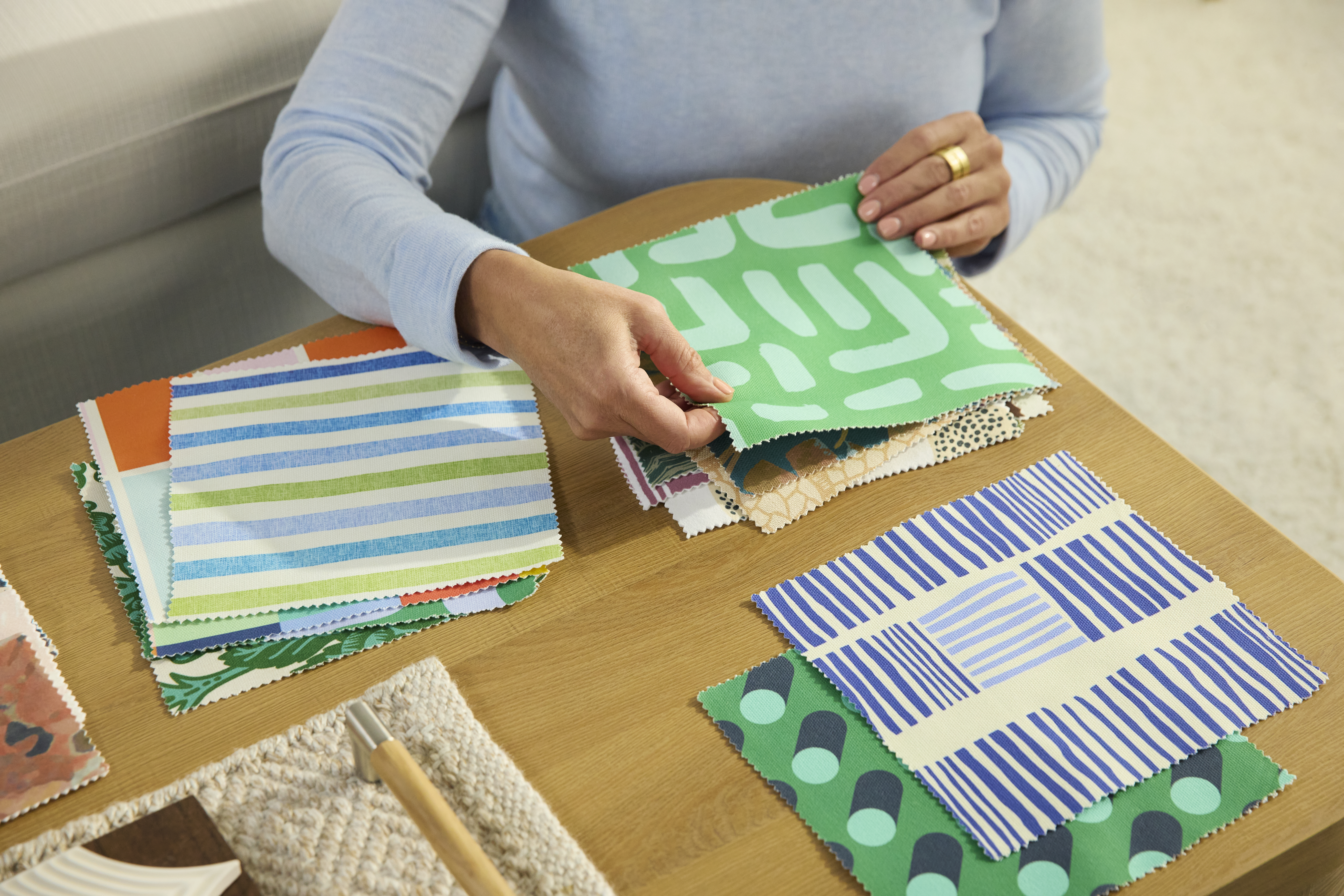 A person sorting through colorful blue and green Spoonflower fabric swatches