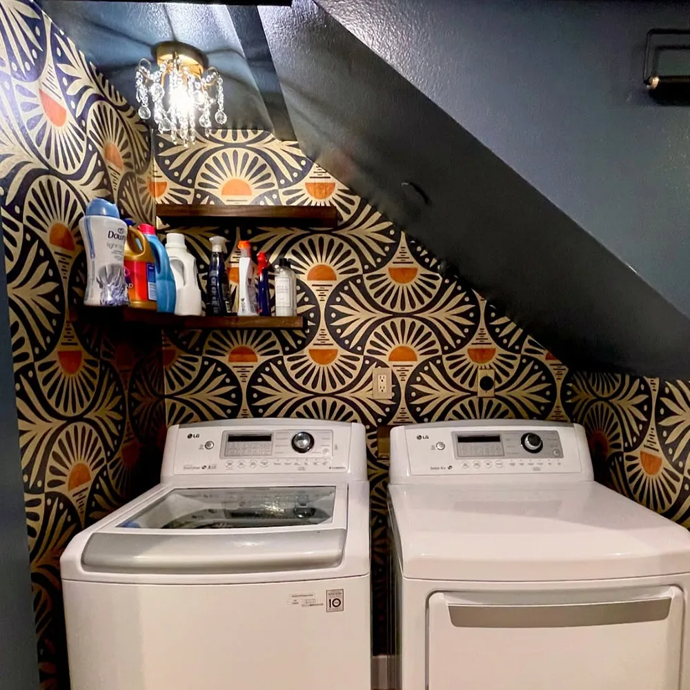 Laundry area with gold metallic wallpaper with an art deco sunset design.