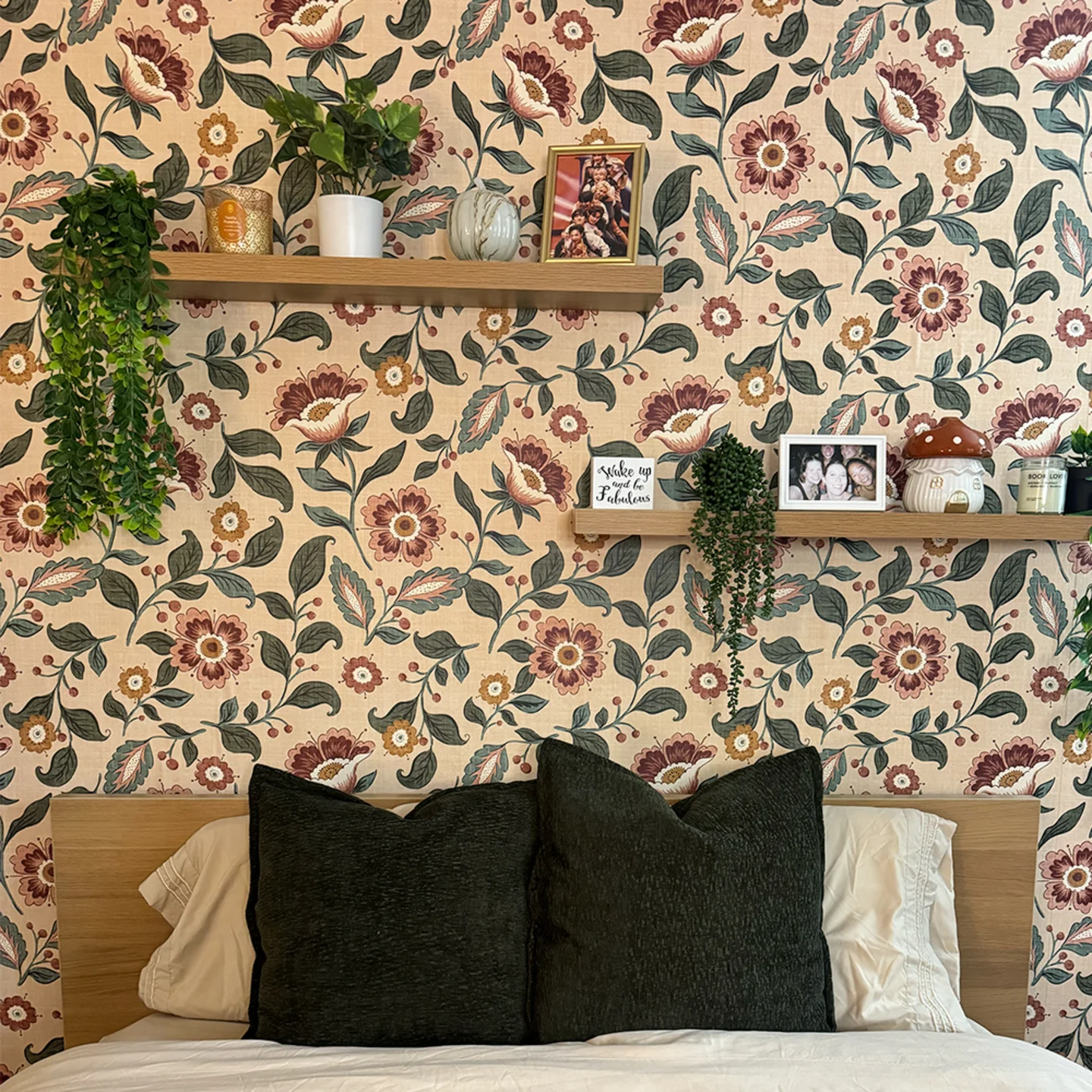Floral wallpaper and floating shelves above a bed in a rented apartment.